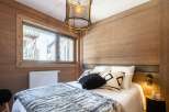 Cozy mountain chalet bedroom with wooden walls and a comfy bed.