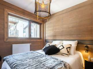 Cozy mountain chalet bedroom with wooden walls and a comfy bed.