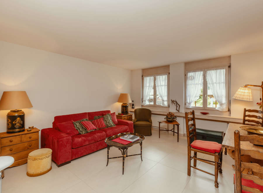 This charming living space features a cozy red sofa, perfect for relaxing.