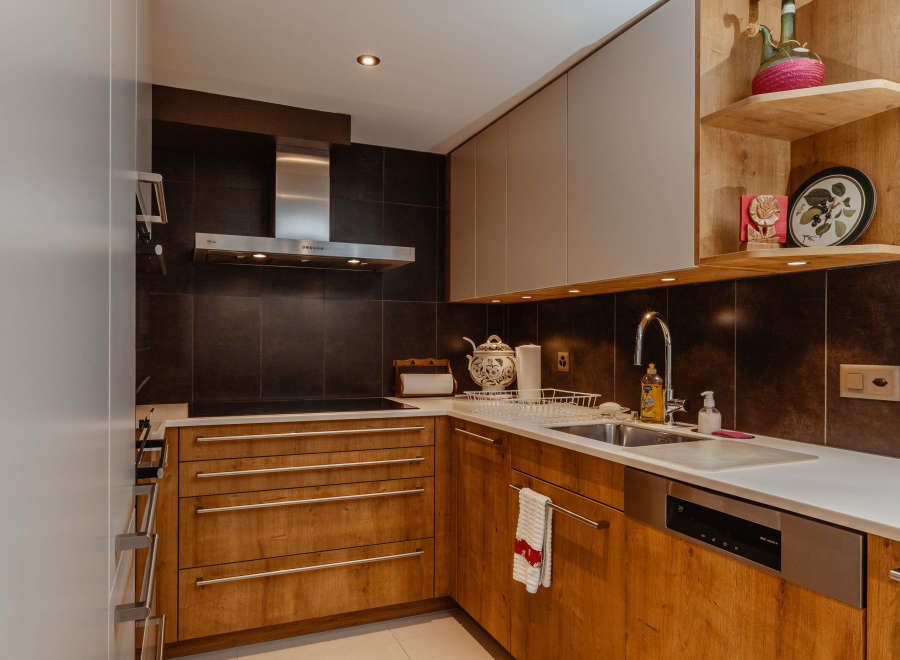 This modern kitchen boasts sleek wooden cabinetry and a stainless steel range hood, creating a warm and inviting atmosphere.