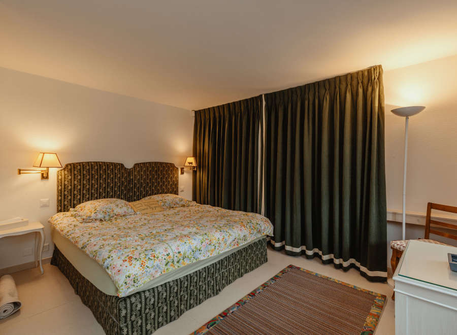 This cozy bedroom features a comfortable bed with floral bedding and a patterned headboard.