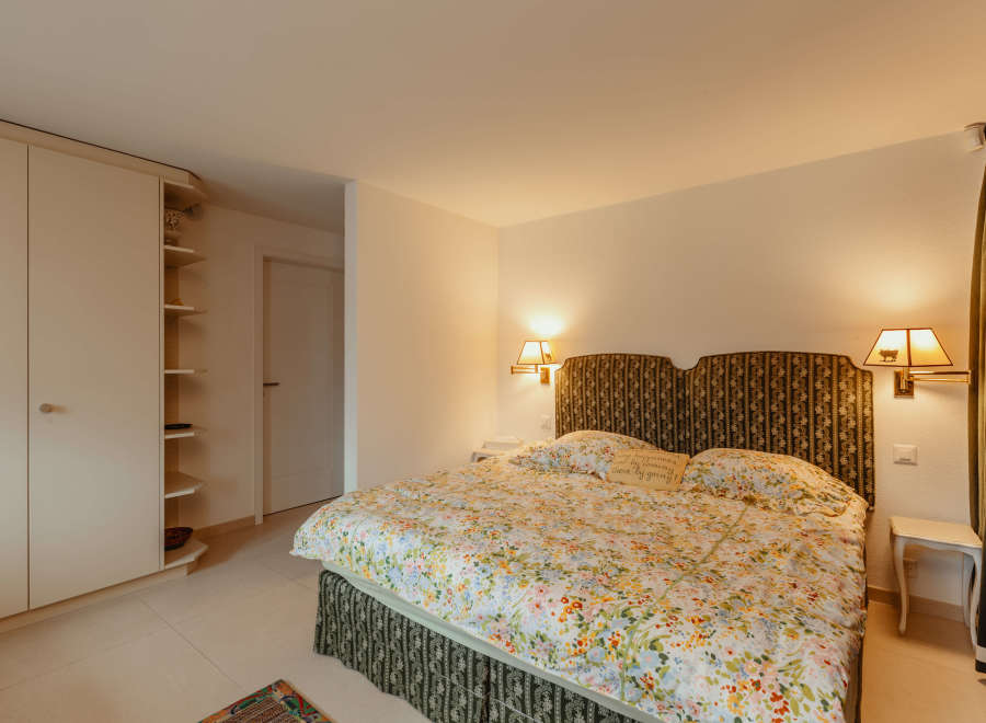 Cozy bedroom with a floral bedspread and patterned headboard.