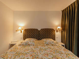 Cozy bedroom with a floral bedspread and a decorative headboard.