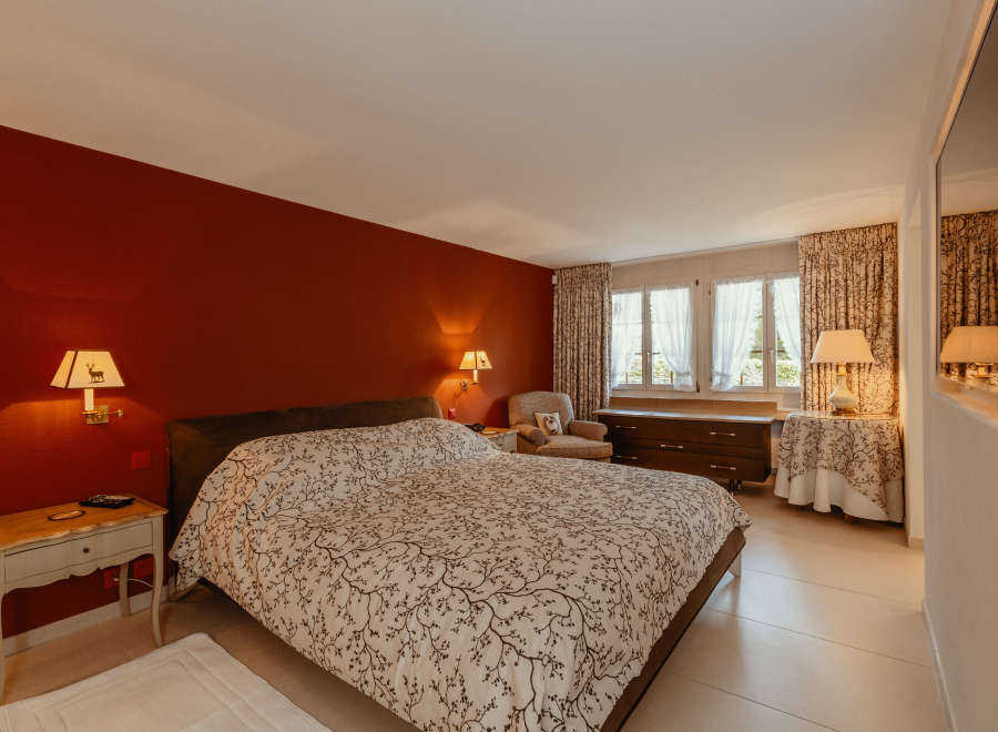 This cozy bedroom features a warm, inviting atmosphere with a rich red accent wall.