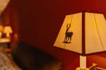 Cozy up in this charming room, featuring a unique lamp with a deer silhouette.