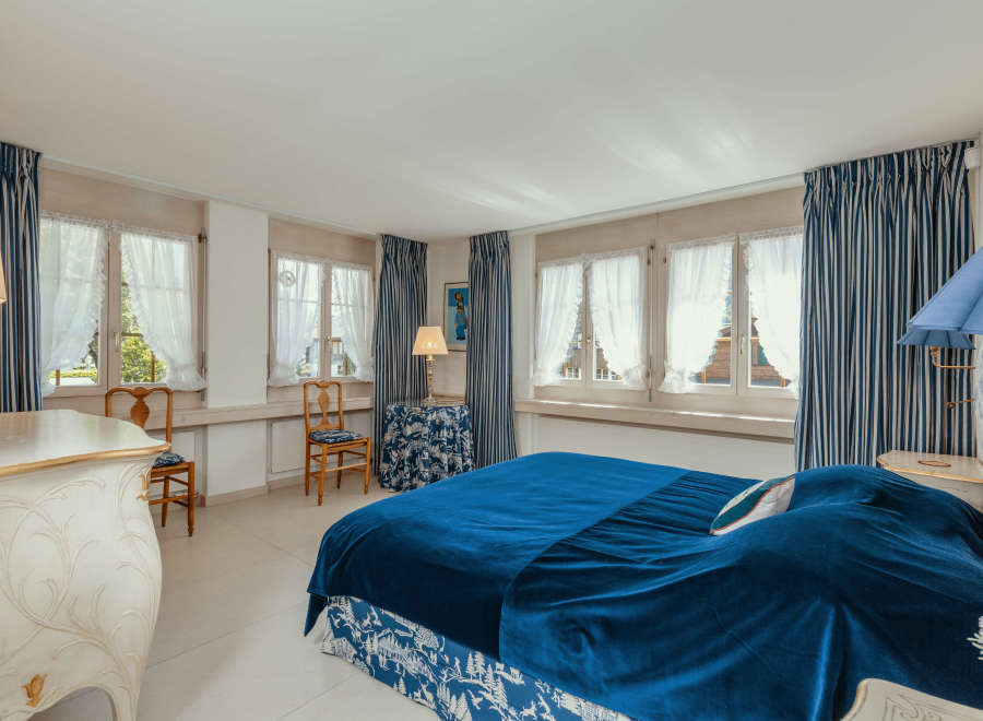 This elegant bedroom features a luxurious blue velvet bedspread and matching curtains, creating a serene and inviting atmosphere.