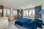 This elegant bedroom features a luxurious blue velvet bedspread and matching curtains, creating a serene and inviting atmosphere.
