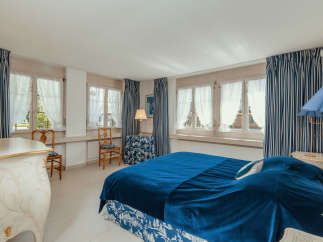 This elegant bedroom features a luxurious blue velvet bedspread and matching curtains, creating a serene and inviting atmosphere.