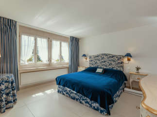 This elegant bedroom features a luxurious blue velvet bed, complemented by matching patterned curtains and a headboard.