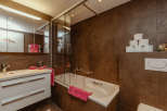 This modern bathroom features a sleek design with brown tiled walls and a bright white vanity.