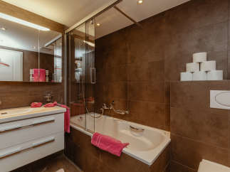 This modern bathroom features a sleek design with brown tiled walls and a bright white vanity.