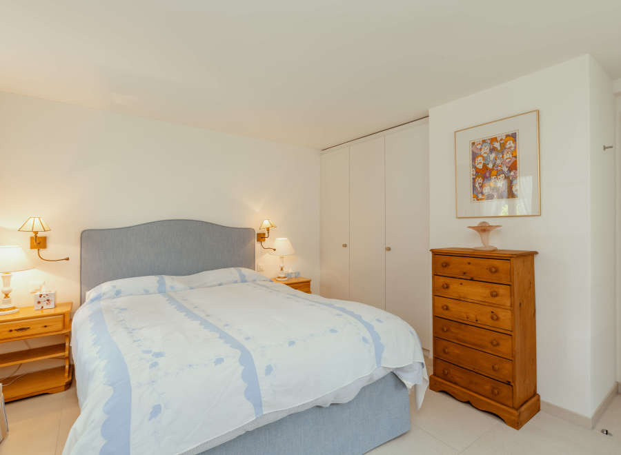 This cozy bedroom features a comfortable bed with a stylish headboard and a beautiful bedspread.