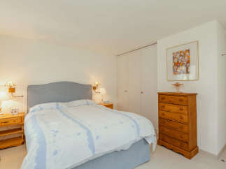 This cozy bedroom features a comfortable bed with a stylish headboard and a beautiful bedspread.