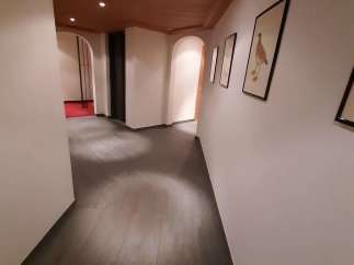 Explore the elegant hallway featuring a warm wooden ceiling and sleek, dark flooring.