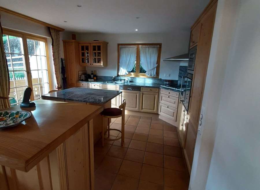 This charming kitchen boasts a warm and inviting atmosphere with its wooden cabinetry and terracotta tile flooring.