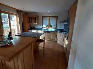 This charming kitchen boasts a warm and inviting atmosphere with its wooden cabinetry and terracotta tile flooring.