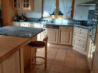 This charming kitchen boasts a warm and inviting atmosphere with its natural wood cabinetry and terracotta tile flooring.