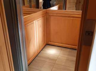 Step into luxury with this stunning elevator, featuring exquisite wood paneling and a sleek, modern design.