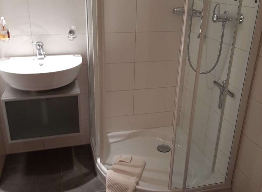 This bathroom features a modern design with a sleek, white sink and a spacious shower.