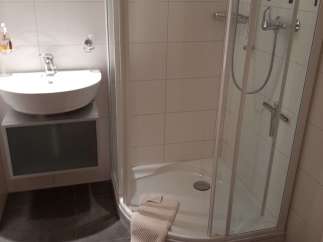 This bathroom features a modern design with a sleek, white sink and a spacious shower.
