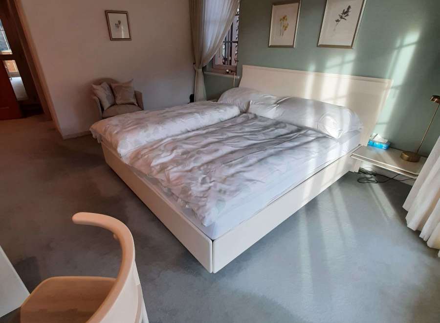 Discover a serene bedroom retreat, featuring a comfortable bed and a stylish chair.