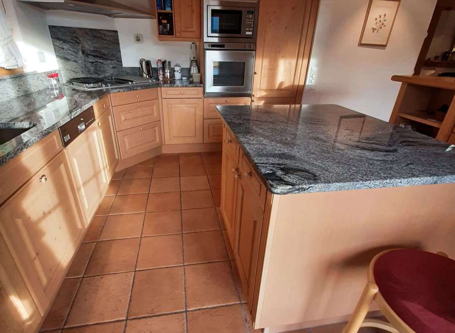 This charming kitchen boasts a warm and inviting atmosphere with its natural wood cabinetry and terracotta tile flooring.