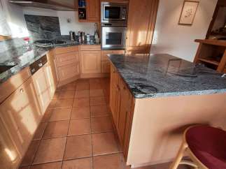 This charming kitchen boasts a warm and inviting atmosphere with its natural wood cabinetry and terracotta tile flooring.