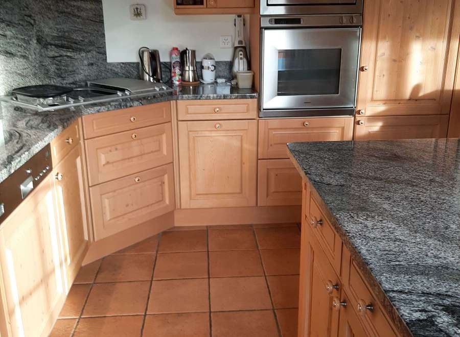 This kitchen boasts beautiful wooden cabinetry and a sleek granite countertop, creating a warm and inviting atmosphere.