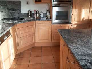 This kitchen boasts beautiful wooden cabinetry and a sleek granite countertop, creating a warm and inviting atmosphere.