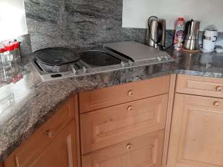 This kitchen boasts a stylish granite countertop and backsplash, creating a sleek and modern aesthetic.