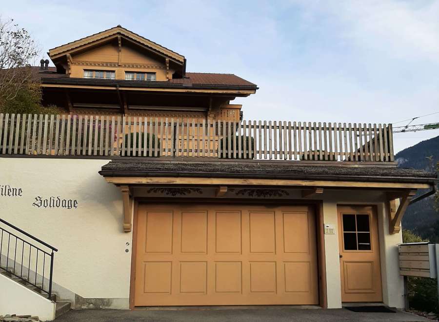 This charming property features a beautiful wooden facade and a welcoming garage door.