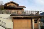 This charming property features a beautiful wooden facade and a welcoming garage door.