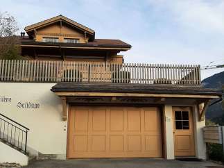 This charming property features a beautiful wooden facade and a welcoming garage door.