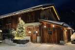 Experience the charm of a cozy wooden chalet nestled in a snowy landscape.