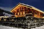 Experience the charm of a cozy wooden chalet nestled in a snowy landscape.