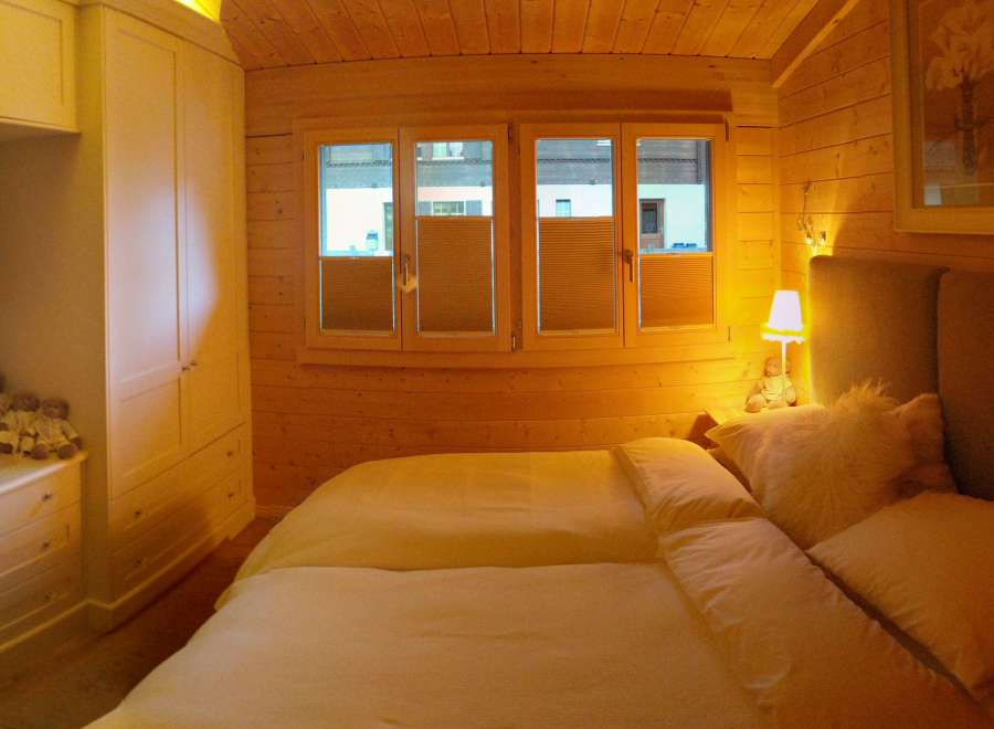 Cozy bedroom with wooden walls and a comfortable bed.
