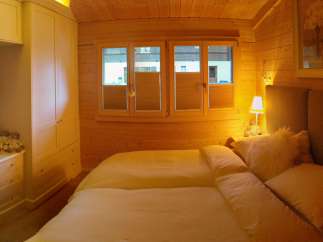 Cozy bedroom with wooden walls and a comfortable bed.