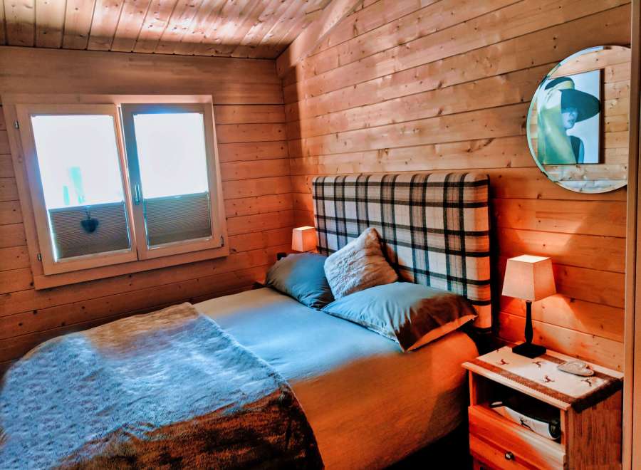Cozy cabin bedroom with wooden walls and a comfortable bed.