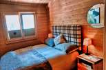 Cozy cabin bedroom with wooden walls and a comfortable bed.