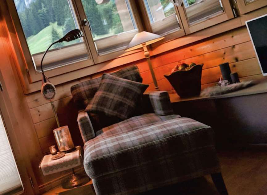 Cozy up in this charming cabin retreat! Enjoy the warmth of the wooden interior and the comfort of the plaid armchair.