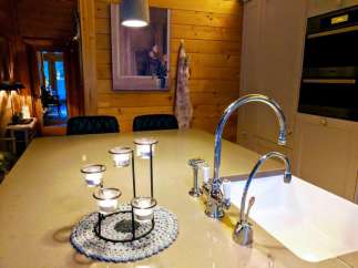 This cozy kitchen features a beautiful wooden wall and a modern sink.