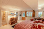 This cozy bedroom features a unique, patterned dresser and a comfortable bed with decorative pillows.