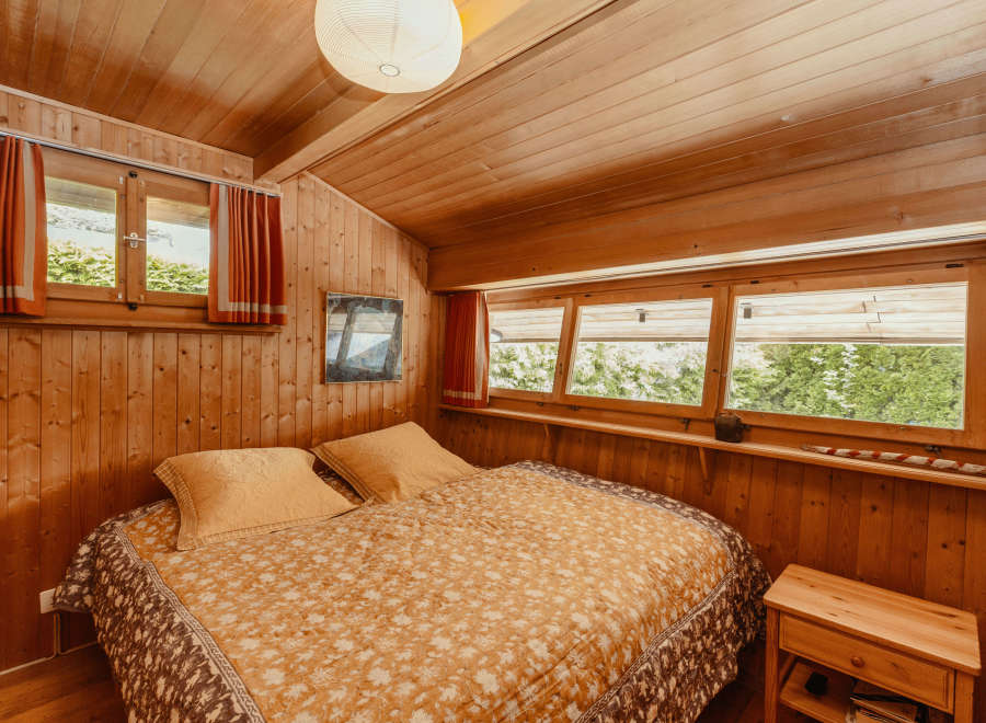 Cozy bedroom with wooden walls and ceiling, creating a warm and inviting atmosphere.