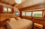 Cozy bedroom with wooden walls and ceiling, creating a warm and inviting atmosphere.