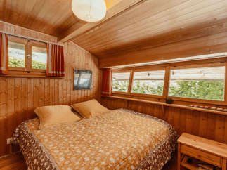 Cozy bedroom with wooden walls and ceiling, creating a warm and inviting atmosphere.