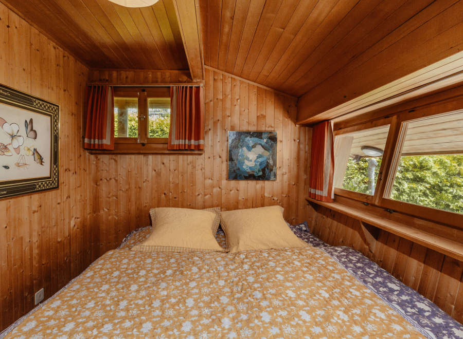 Cozy bedroom with wooden walls and ceiling, creating a warm and inviting atmosphere.