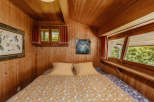 Cozy bedroom with wooden walls and ceiling, creating a warm and inviting atmosphere.