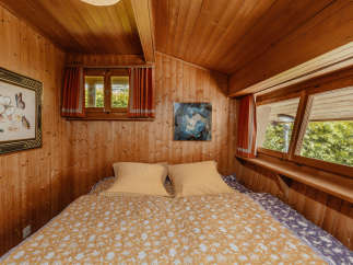 Cozy bedroom with wooden walls and ceiling, creating a warm and inviting atmosphere.