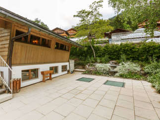 Discover a charming property featuring a unique wooden facade and a welcoming outdoor patio.