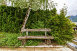 Enjoy the tranquility of this charming outdoor space, featuring a rustic wooden bench nestled amidst lush greenery.